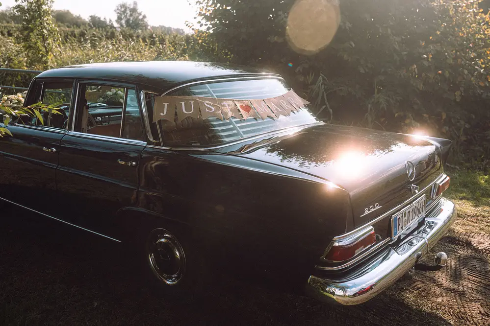 Mercedes-Benz 200 wedding car, classic with Just Married bunting. Backlight, lens flares. Leica M10 M11. Tiffen Black Pro Mist.