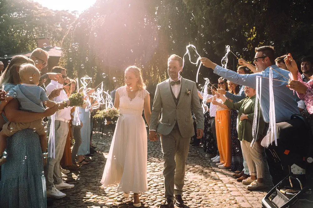 Guests forming a guard of honour. Soap bubbles. Happy couple. Leica M11.