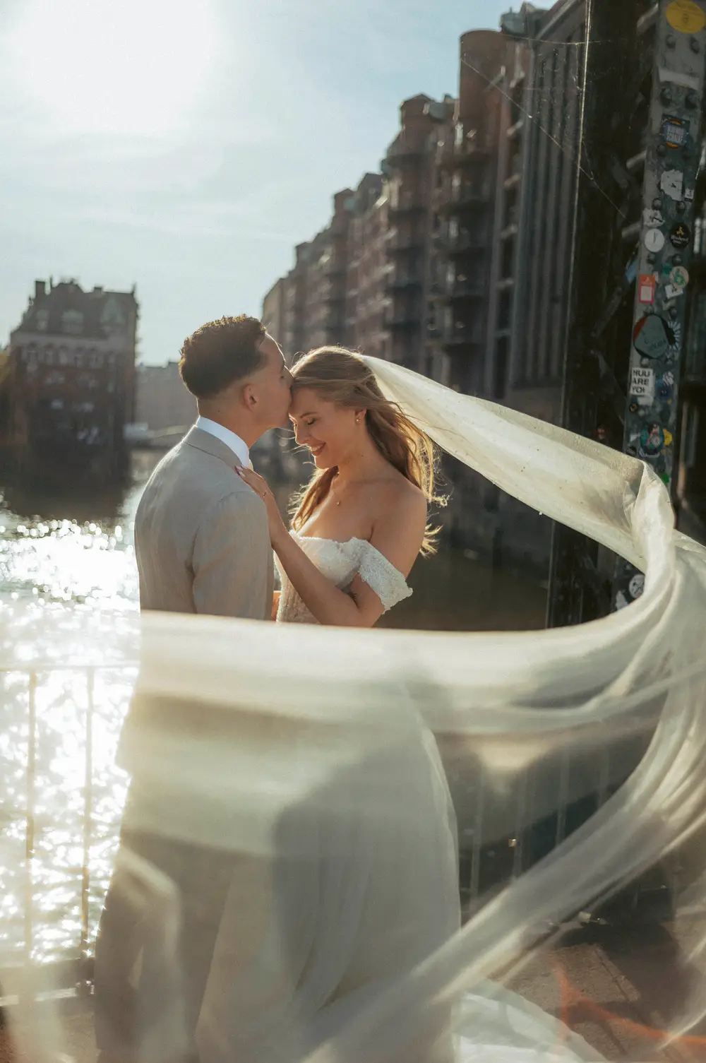 Wedding photography Hamburg Speicherstadt, Fleetschlösschen, Wasserschloss, Elbschlösschen, Elbschloss. Couple in backlight. Long bridal veil blowing in the wind. Leica M11.